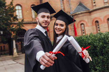 Group of  two successful students on their graduation day with certificate on hands!