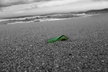Grünes Glas am Sandstrand nahe dem Meer