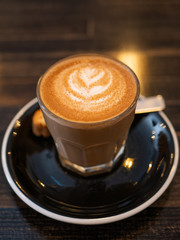 cup of coffee with cream on wooden background