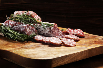 thinly sliced salami sausages on a wooden texture on the background.