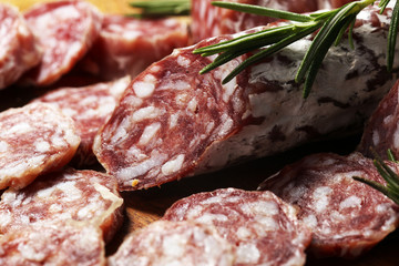 thinly sliced salami sausages on a wooden texture on the background.