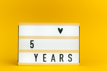 Photo of a light box with text, 5 YEARS, on isolated yellow background