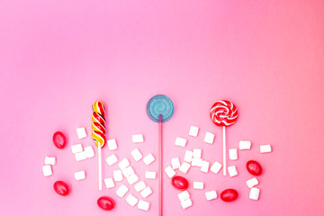 Obraz na płótnie Canvas Flat lay composition with yummy lollipops and marshmallows and space for text on pink background