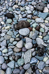 Sea tumbled round rocks on a beach with a few volcanic rocks mixed in, as a nature background