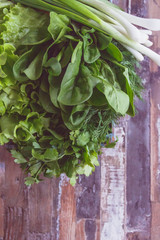 Set of seasonal greenery on the wooden background. Healthy food