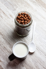 BLACK BREAKFAST MUG WITH MILK AND CHOCOLATE CEREAL JAR ON CLEAR WOOD BACKGROUND