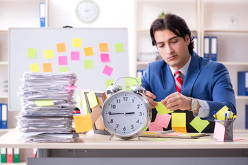 Young male handsome employee in conflicting priorities concept 
