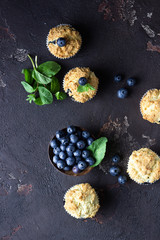 Obraz na płótnie Canvas Blueberry muffins with fresh berries and mint leaves on dark brown stone background. Copy space.