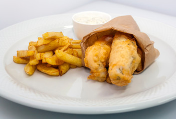 traditional english fish and chips with tartar sauce on a white plate