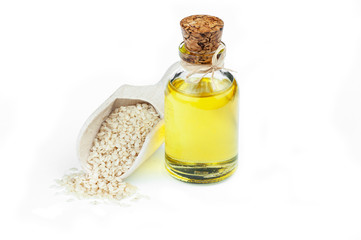 Glass bottle of sesame oil and raw sesame seeds in wooden shovel isolated on white background. Uncooked sesame background concept with copy space