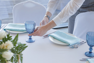 Wedding table setting. The waiter in a gray suit and white shirt serves the table