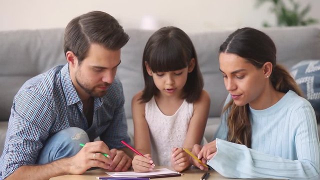 Parents teaching child daughter talking drawing coloring picture with pencils