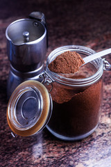 FIRST PLANE OF SPOON WITH GROUND COFFEE ON GLASS JAR