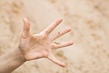 Open children's palm covered with grains of sand.
