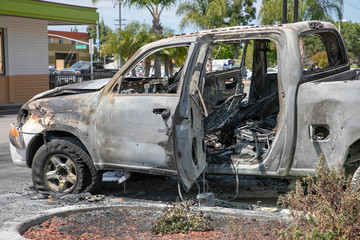 Burned car left abandoned in the parking lot. Ruined, melted, destroyed automobile.  Car insurance claim.