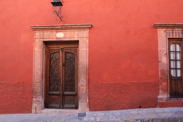 Ancient red facade with beautiful wood door and lamp