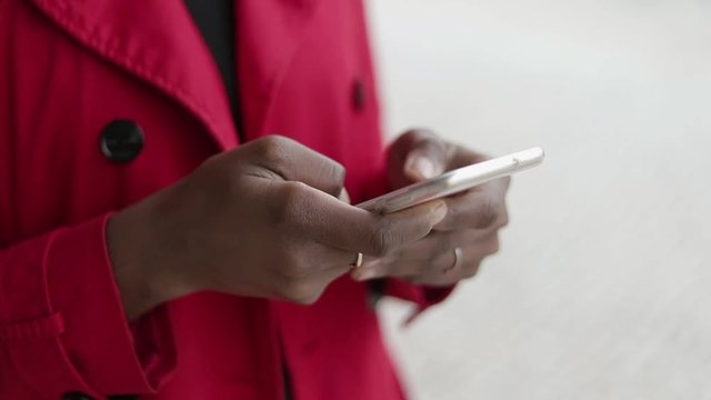 Close up shot of Afro-american young female hands with gold rings swiping and pinching photos on phone. Lifestyle concept