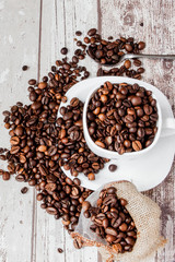 Black coffee in white cup and coffee beans on light wooden background. Top view, space for text