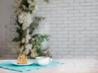 a piece of cake and a Cup of tea, a white brick wall and plants