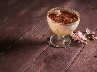 chocolate cream with coffee dessert in a glass container and the hand with a spoon