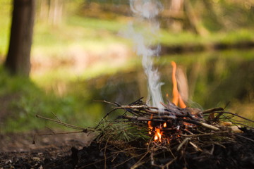 A smoke over fireplace on the riverbank out in the forest.