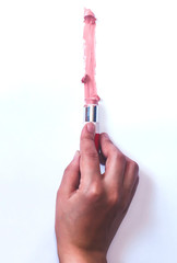 Female hand with pink lipstick drawing a line on white paper