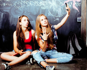 Fototapeta premium back to school after summer vacations, two teen girls in classroom with blackboard painted together
