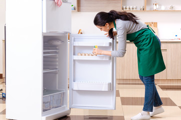 Young woman cleaning fridge in hygiene concept 