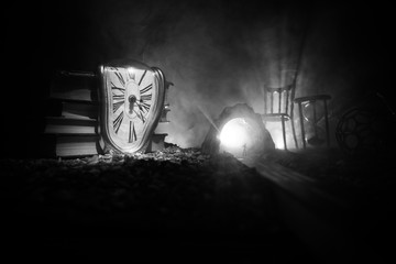 Time concept. Silhouette of a man standing between hourglasses with smoke and lights on a dark...