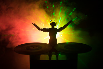 Dj club concept. DJ mixing, and Scratching in a Night Club. Man silhouette on vinyl turntable,...