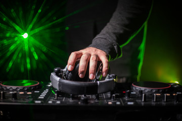 DJ Spinning, Mixing, and Scratching in a Night Club, Hands of dj tweak various track controls on...