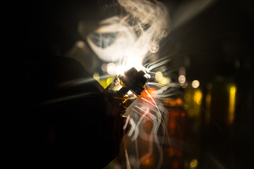 Vape concept. Electronic Cigarette vape explosion. Smoke clouds and vape liquid bottles on dark background. Light effects. Useful as vape advertisement.
