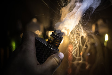 Vape concept. Electronic Cigarette vape explosion. Smoke clouds and vape liquid bottles on dark...