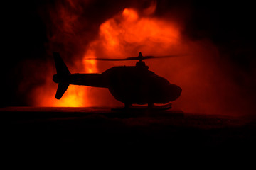Silhouette of military helicopter ready to fly from conflict zone. Decorated night footage with helicopter starting in desert with foggy toned backlit. Selective focus.