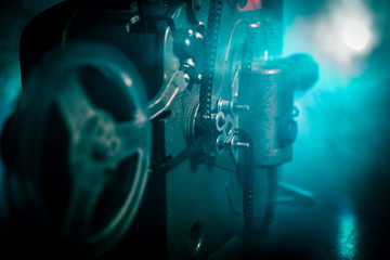 Old vintage movie projector on a dark background with fog and light. Concept of film-making.