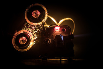 Old vintage movie projector on a dark background with fog and light. Concept of film-making.