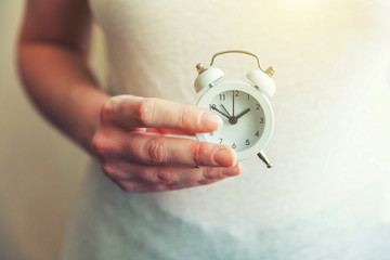 Female woman hands holding ringing twin bell vintage classic alarm clock. Rest hours time of life...