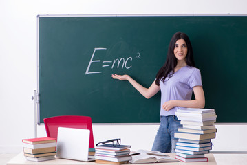Young female teacher student in front of green board 
