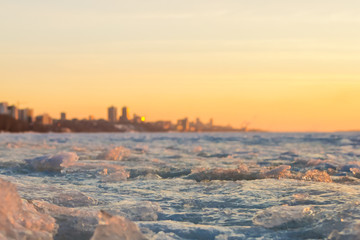 View of city in early spring in the sunset with ice pack in foreground and the city in background.