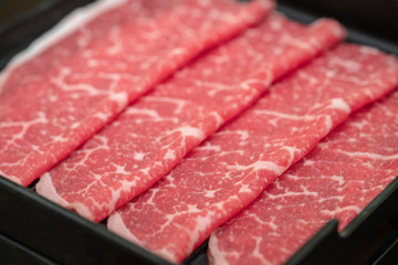 Close up of raw meat in black tray.