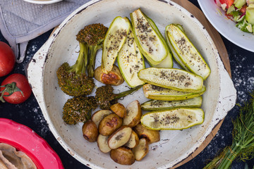 Baked, roasted vegetables on frying pan skillet. Potato, zucchini, potato with spices. Top above view
