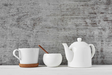 Cup of tea, teapot and sugar bowl on gray