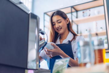 Pretty young asian waitress standing arms crossed in cafeteria.Coffee Business owner Concept.  barista in apron smiling at camera in coffee shop counter