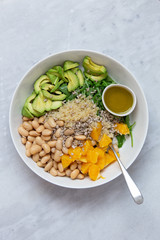 Vegetarian salad with avocado, white beans, arugula, spinach, sunflower seeds, orange and quinoa flavored with olive oil with lemon and Himalayan salt