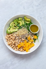 Vegetarian salad with avocado, white beans, arugula, spinach, sunflower seeds, orange and quinoa flavored with olive oil with lemon and Himalayan salt