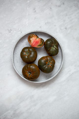 Organic Tomato Marmande black  on marble backgroun with copy space. Vegan product