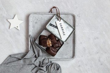 chocolate candy with nuts and dates in gift box on white marble background with copy space