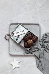 chocolate candy with nuts and dates in gift box on white marble background with copy space