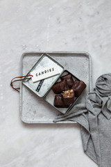 chocolate candy with nuts and dates in gift box on white marble background with copy space