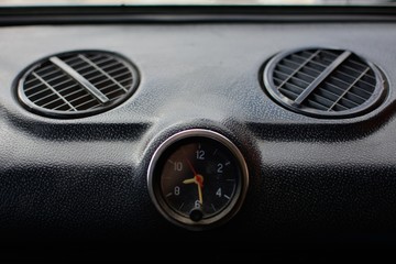 Black control panel with heater grilles and a clock with hands in an old Russian car